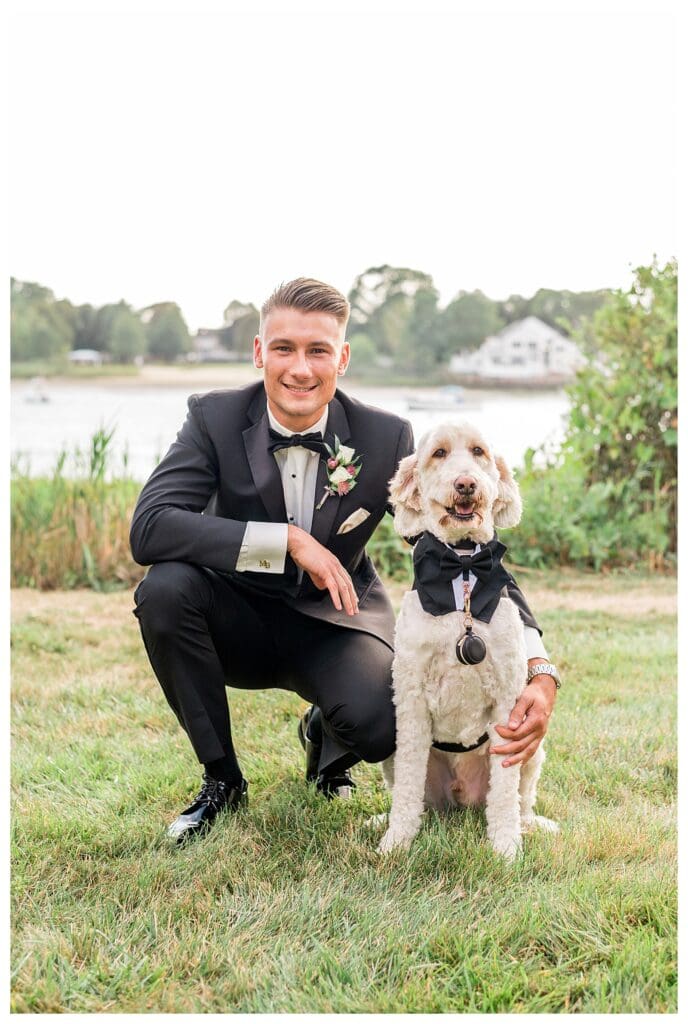 Groom kneeling next to his dog, Ollie, during outdoor portraits.