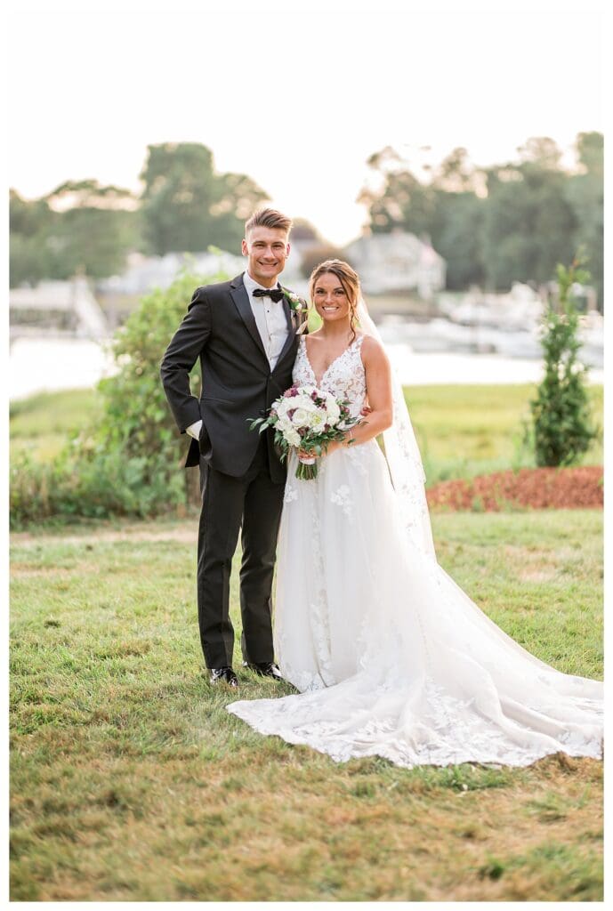 Bride and groom standing in front of lush greenery.