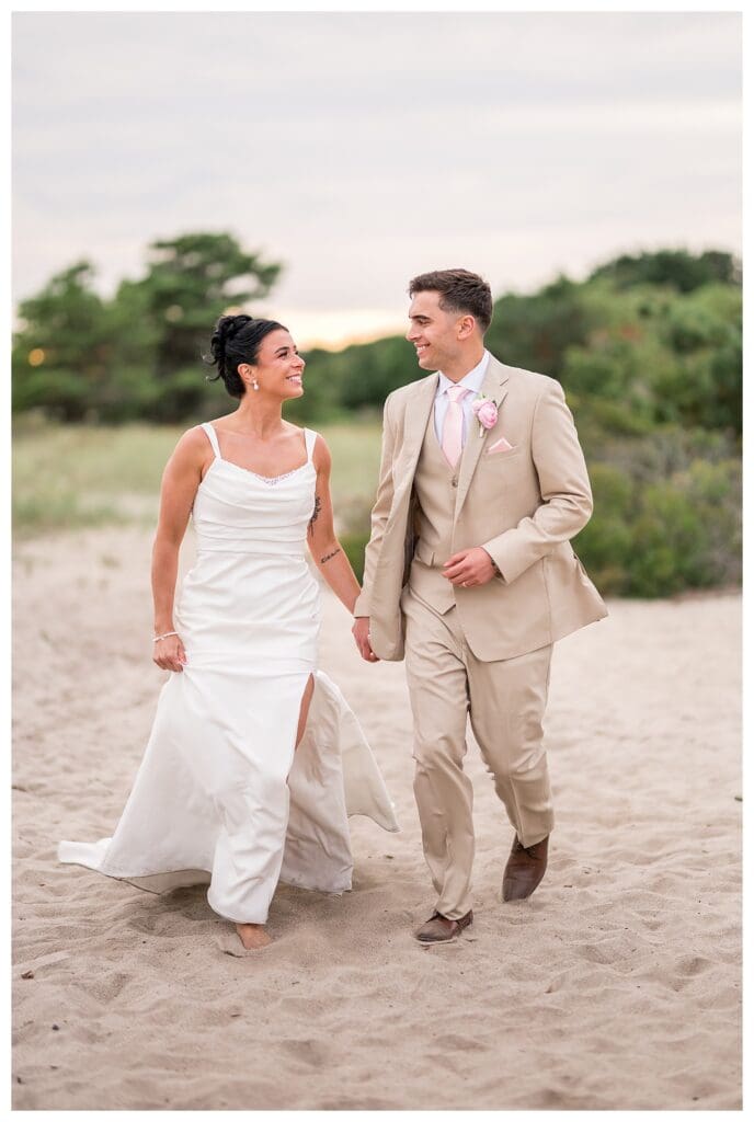 Bride and groom walking on Wychmere's beach.