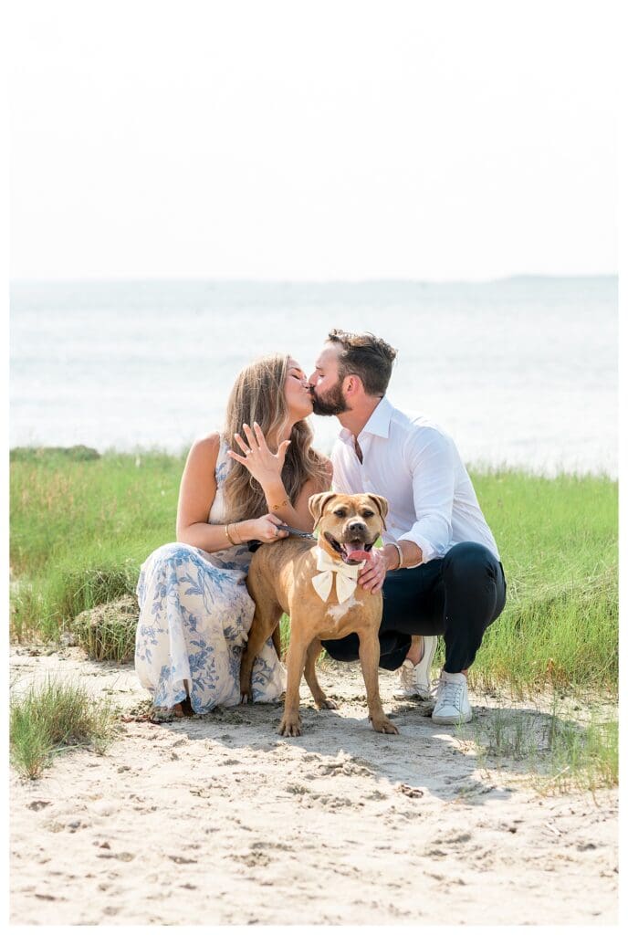 Reid and Libby kissing over their dog Marmalade during their Cape Cod engagement session