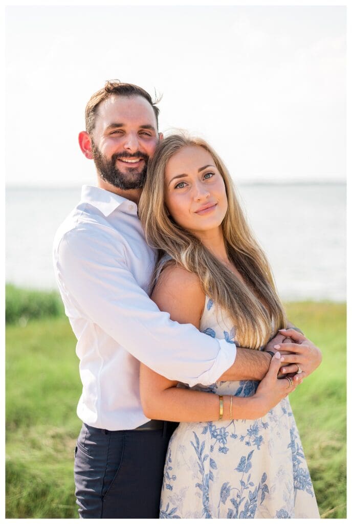 Reid hugging Libby from behind on the beach in Yarmouth, Cape Cod moments after proposing