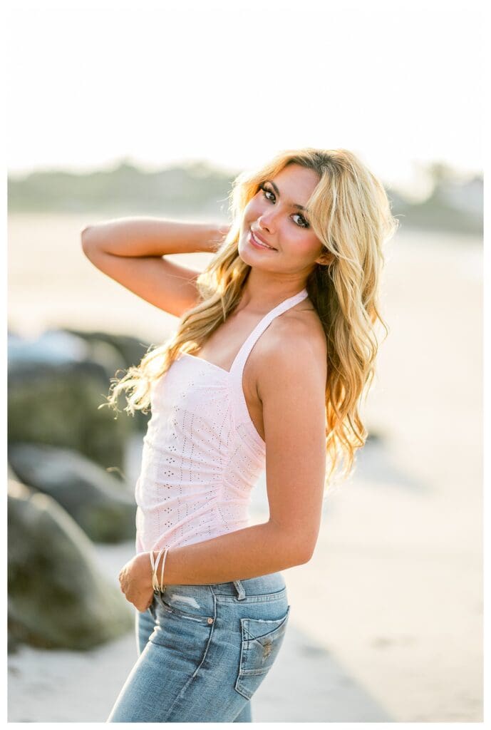 Senior girl posing effortlessly on a sandy beach in Cohasset, Massachusetts