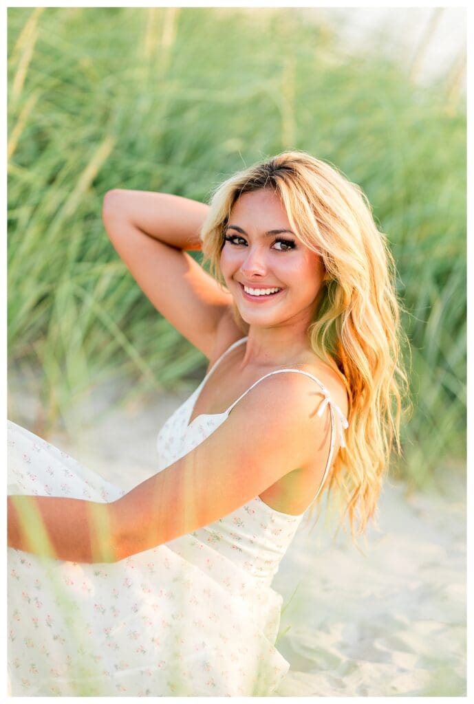 High school senior framed by dune grass during a coastal session in Cohasset