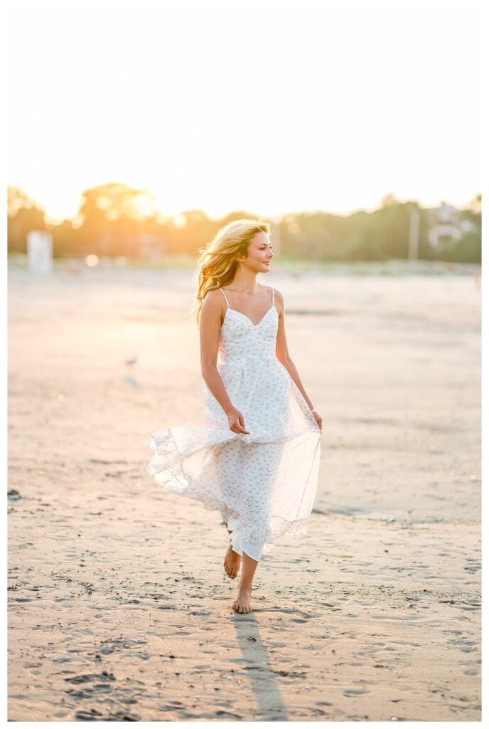 Senior girl walking barefoot along the shoreline in Cohasset, MA