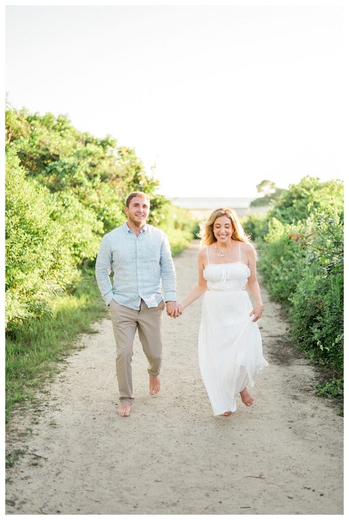 Couple walking a sandy path at The Knob in Falmouth, MA with their golden retriever, Morgan