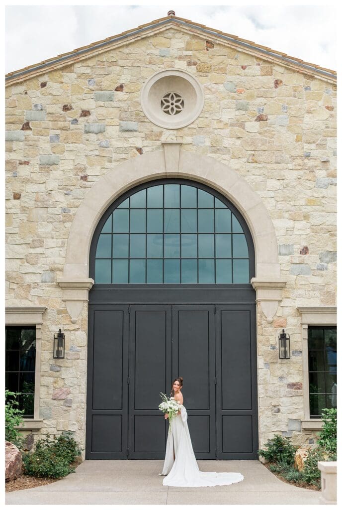 Bride smiling in front of an epic black arched door during outdoor California destination wedding.