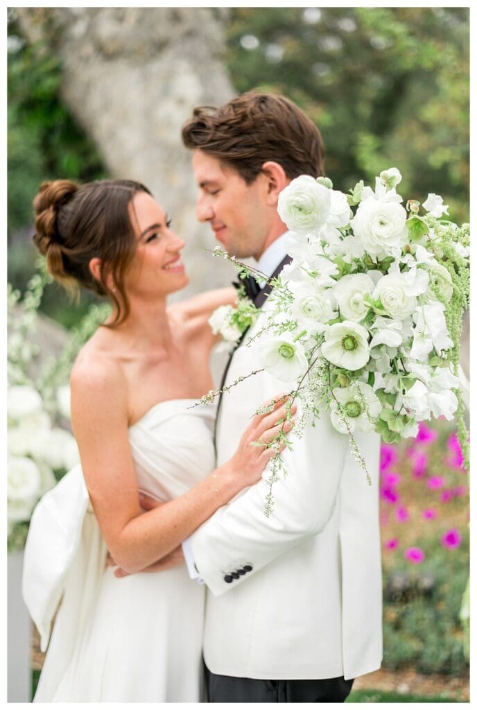 Bride and groom sharing an intimate moment surrounded by lush landscaping at Monserate Winery