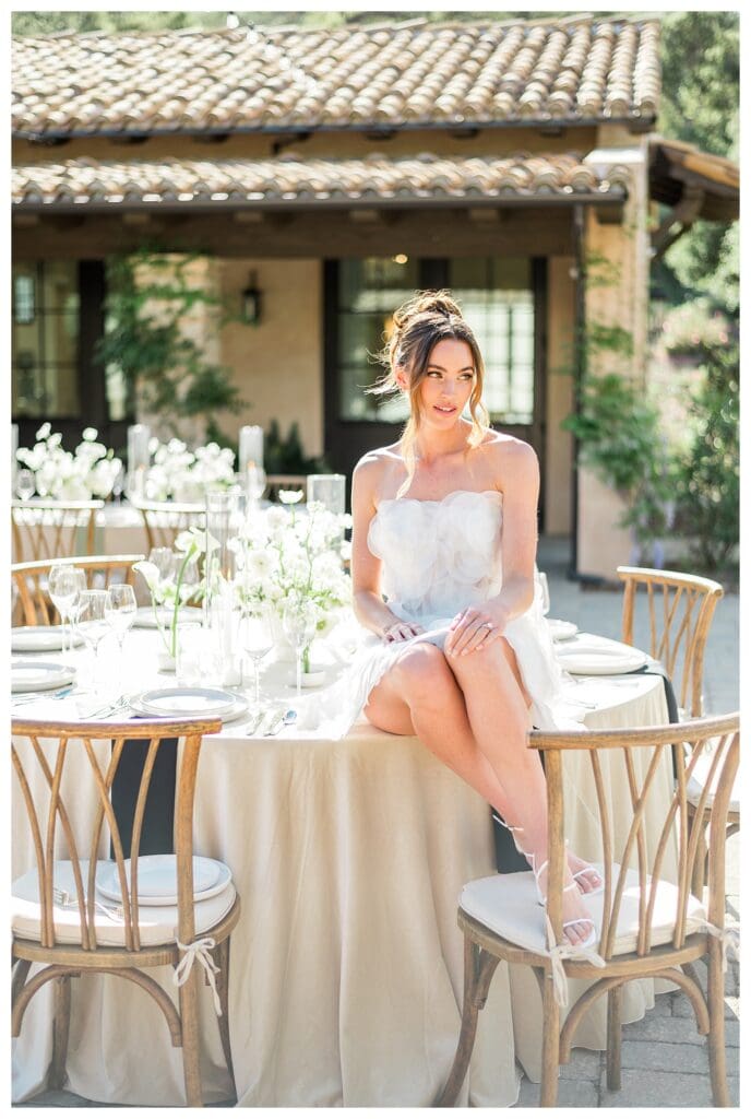 Bride sitting on a table at outdoor California destination wedding