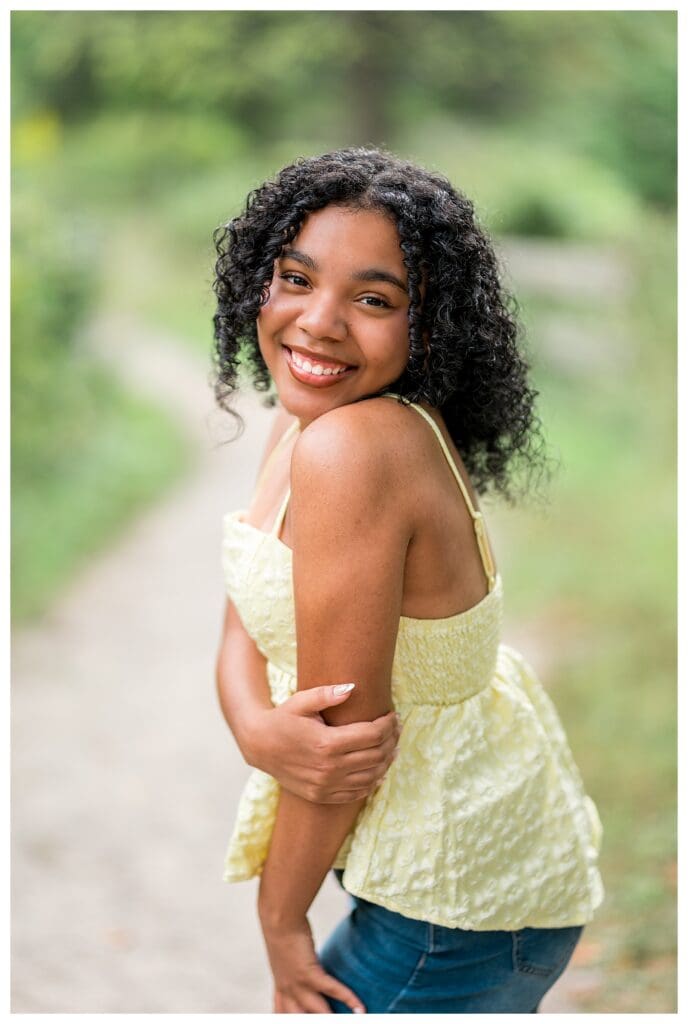 Close up portrait of curly haired senior smiling in warm evening light.
