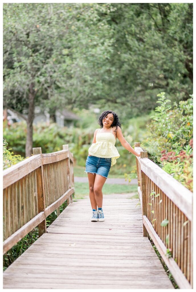 High school senior leaning against wooden bridge for natural Andover High Senior Portraits.
