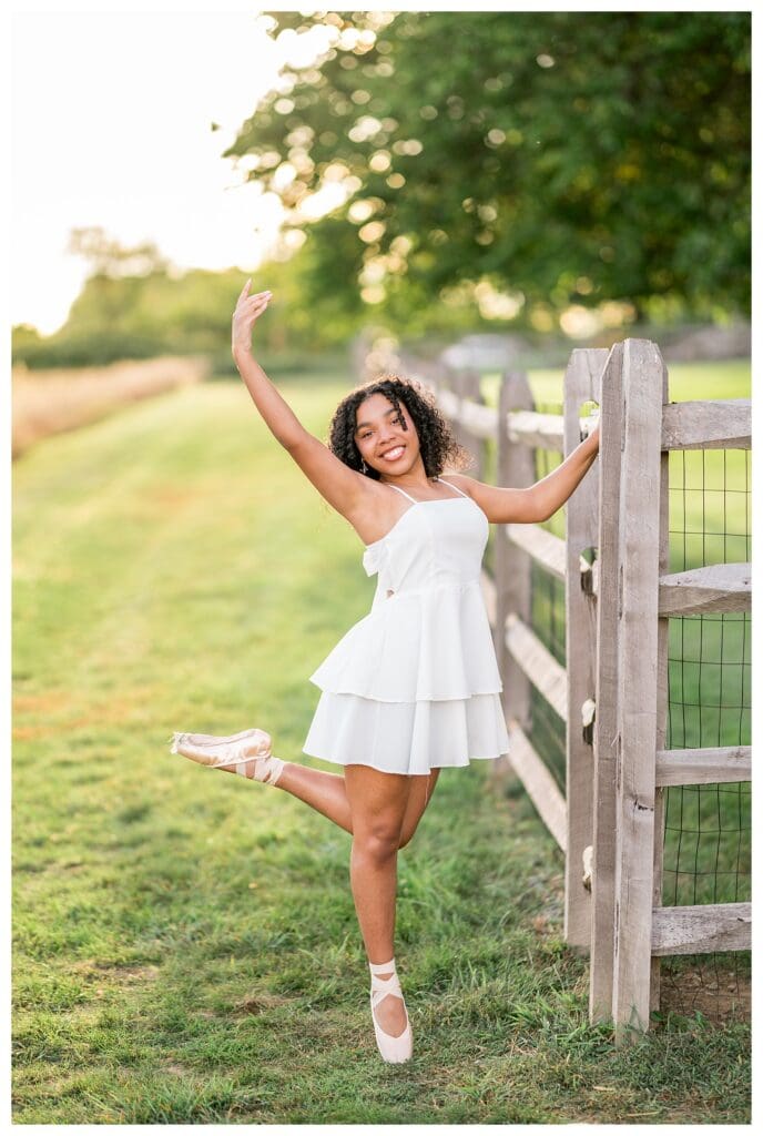 Massachusetts senior portrait of dancer posing in pointe shoes in a green field.