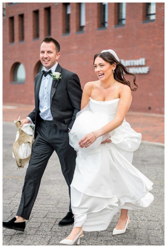 Newlyweds walking through Boston waterfront park.