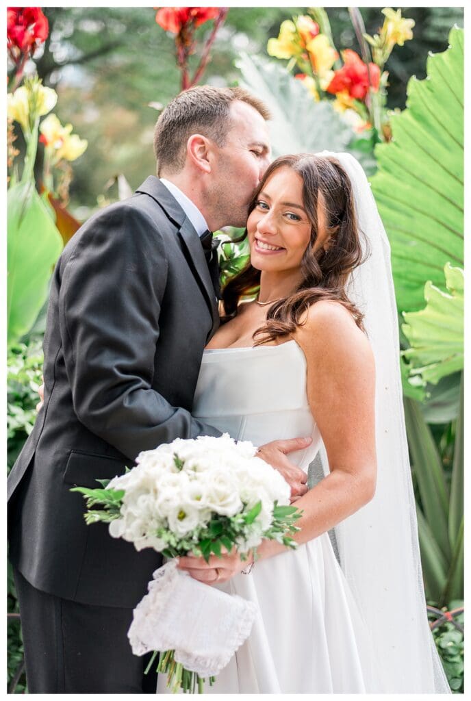 Groom holding bride close at Christopher Columbus Park.