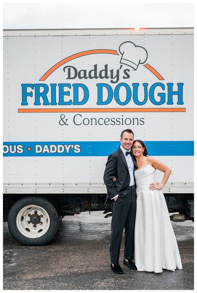 Couple laughing in front of food truck near Boston harbor.