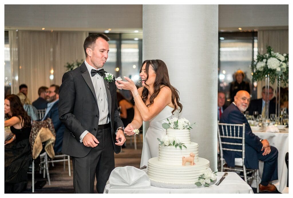 Bride and groom cutting cake at waterfront Boston reception.