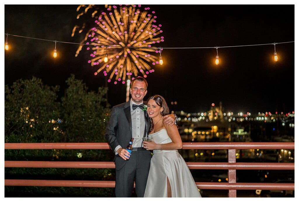 Bride and groom hugging on a balcony during fireworks at their Boston Marriott Long Wharf wedding.