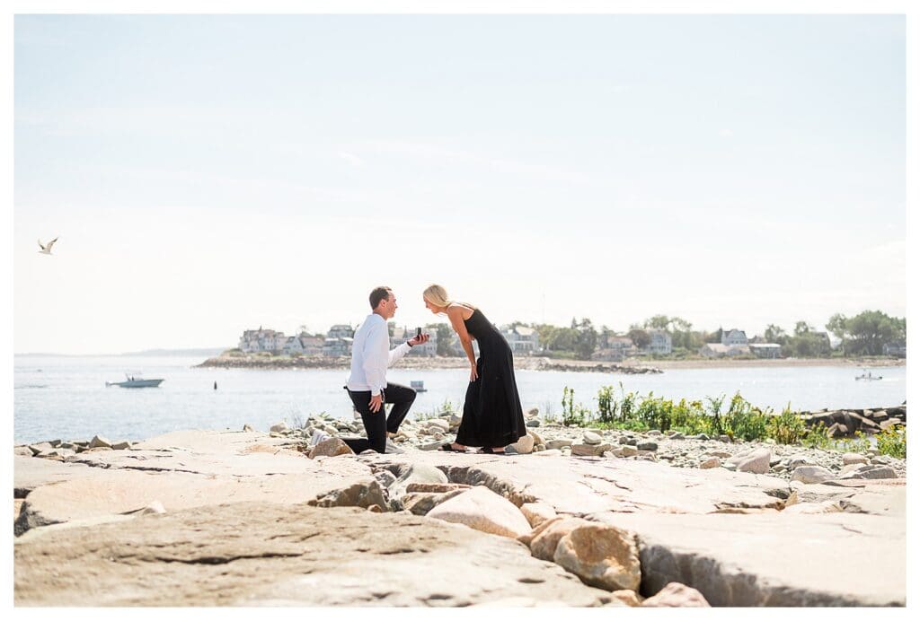 Side angle of emotional beach proposal with bride-to-be reacting to engagement ring.