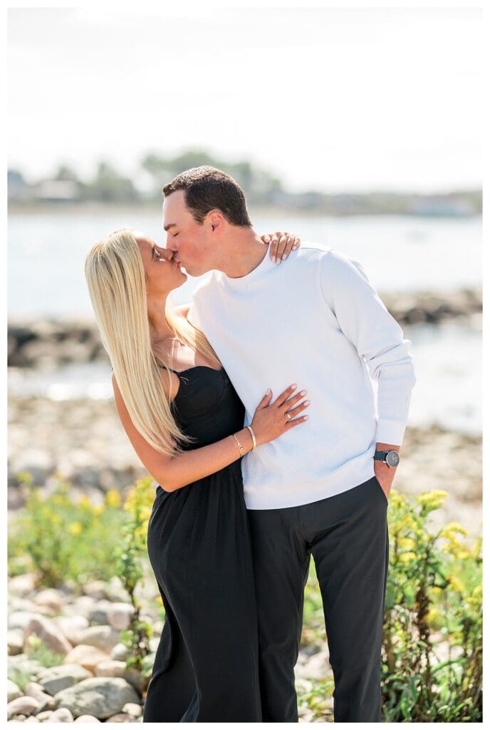 Close-up of couple kissing with sunlight reflecting off the water behind them.