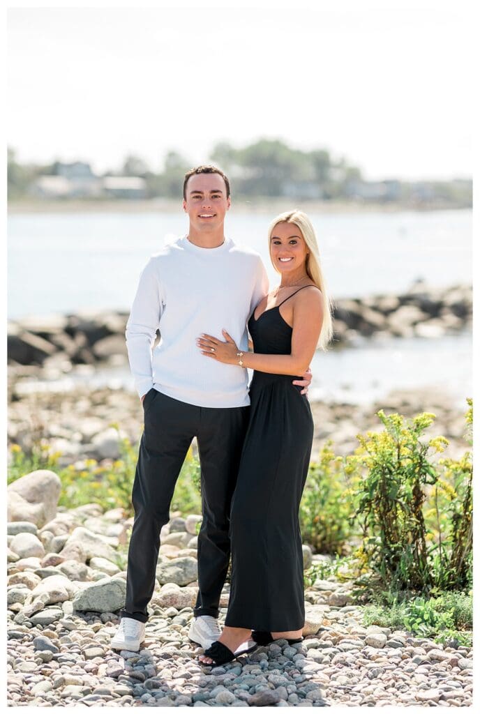 Newly engaged couple embracing on the shoreline after the proposal.