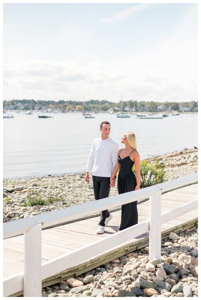 Couple walking along wooden boardwalk overlooking the harbor.