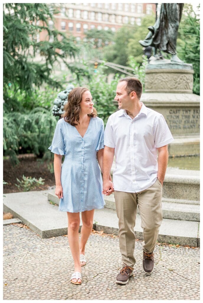Couple walking hand in hand near fountain in Boston Public Garden engagement session