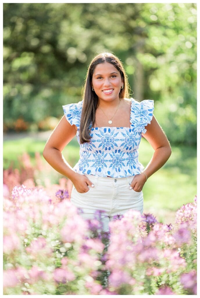 Senior girl standing in flowers with soft summer glow