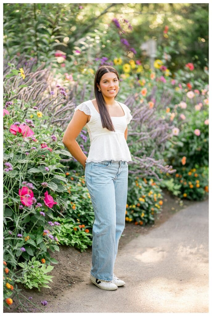 Senior girl posing in white top with garden blooms behind her
