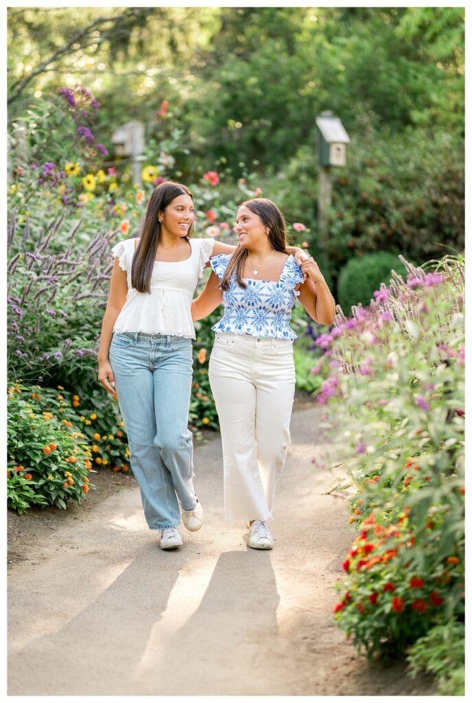 Twin sisters walking through flowers during senior session