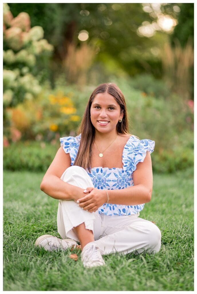 Senior girl sitting in grass with soft summer light