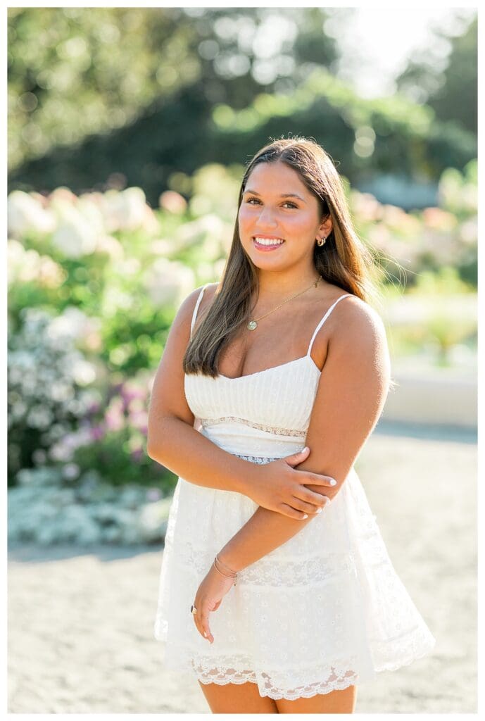 Senior photo of girl smiling in white dress with flowers
