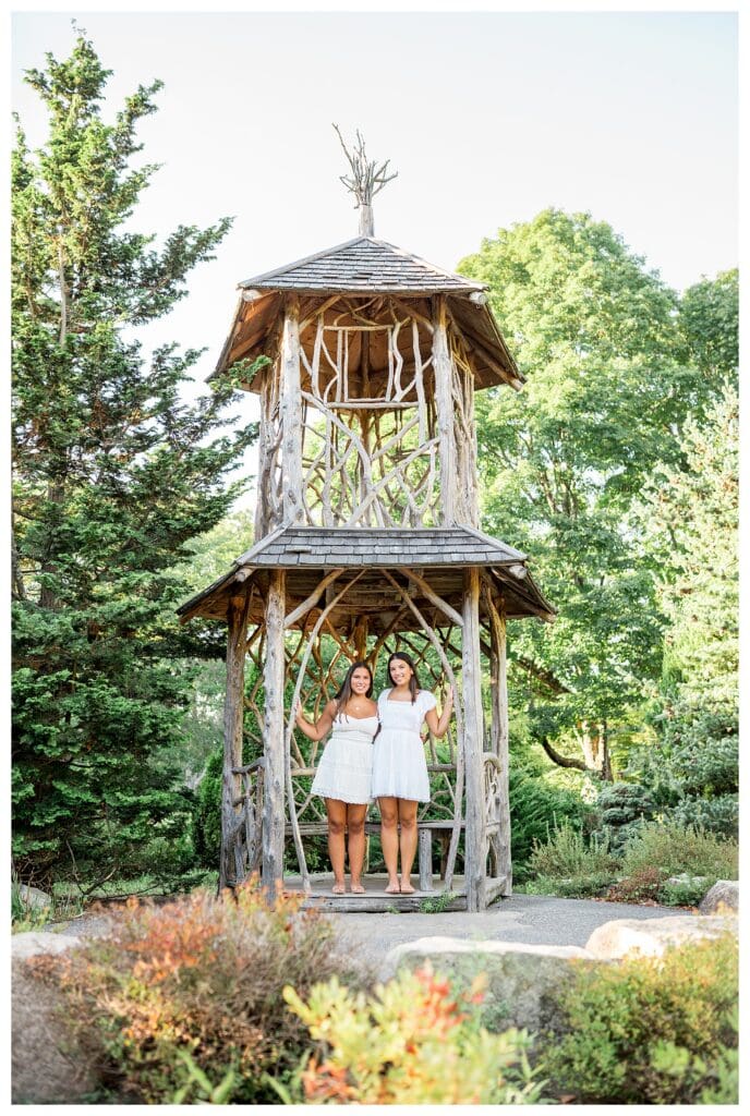 Twin sisters posing in white dresses with flowers at Elm Bank