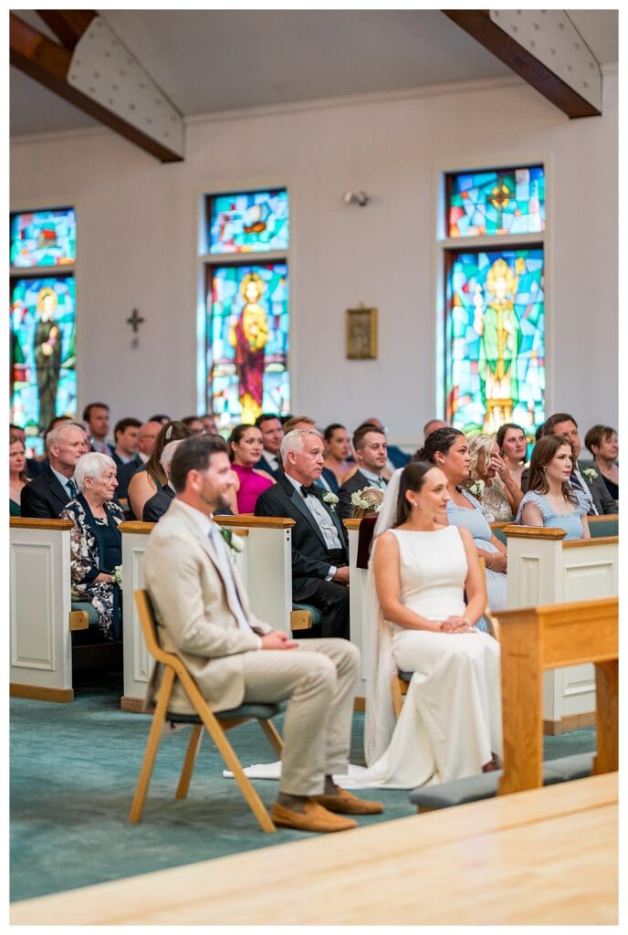 Wedding ceremony guests inside bright church