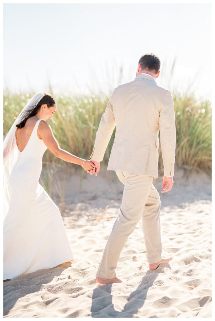 Groom leading bride through beach grass