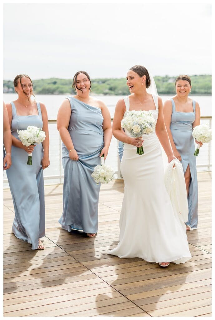 Bride walking with bridesmaids in blue dresses at coastal Massachusetts wedding