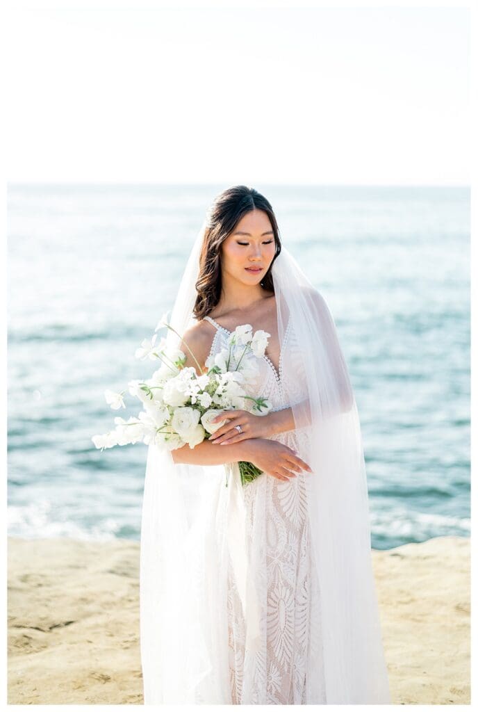 Bride portrait with soft expression holding white bouquet at Sunset Cliffs San Diego.