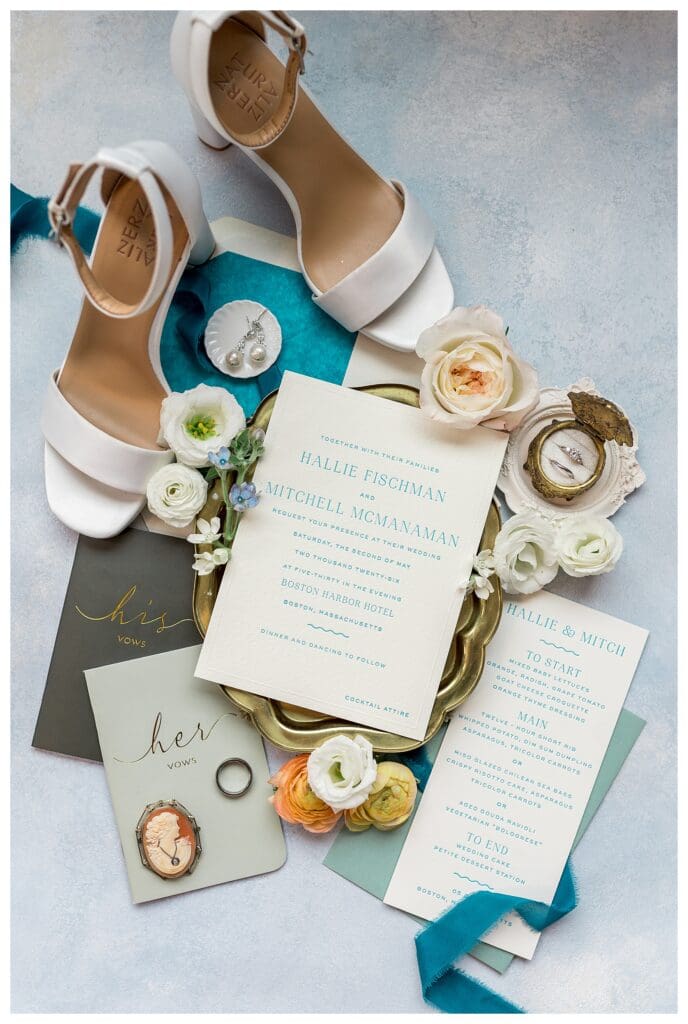 Flat lay of wedding invitation suite, rings, and bridal accessories at Boston Harbor Hotel