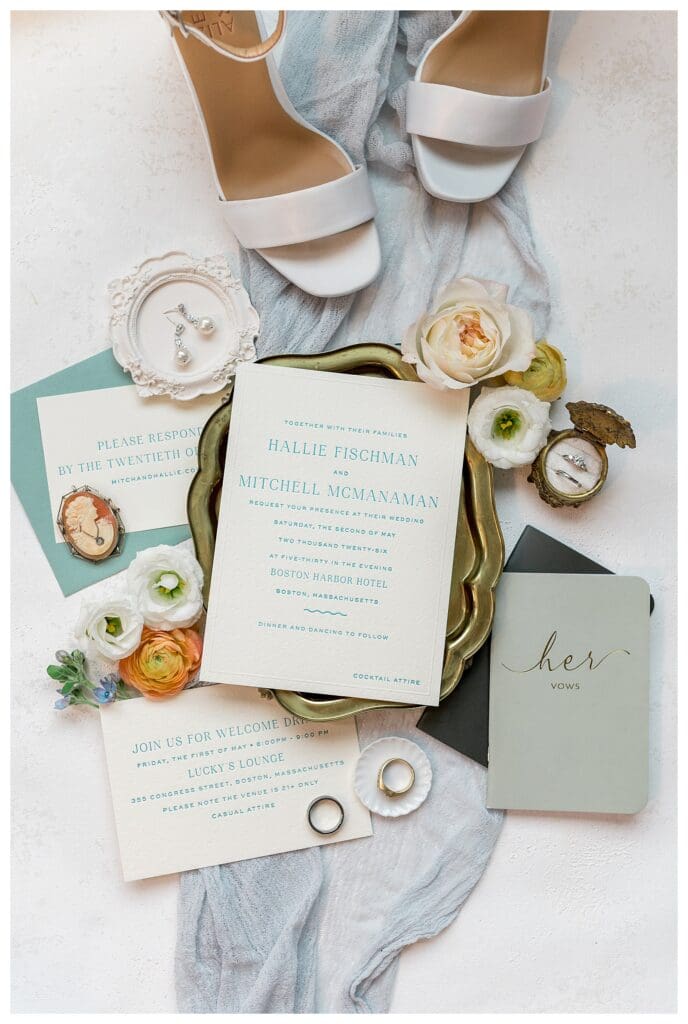 Wedding detail flat lay with rings, vow book, and florals at Boston Harbor Hotel