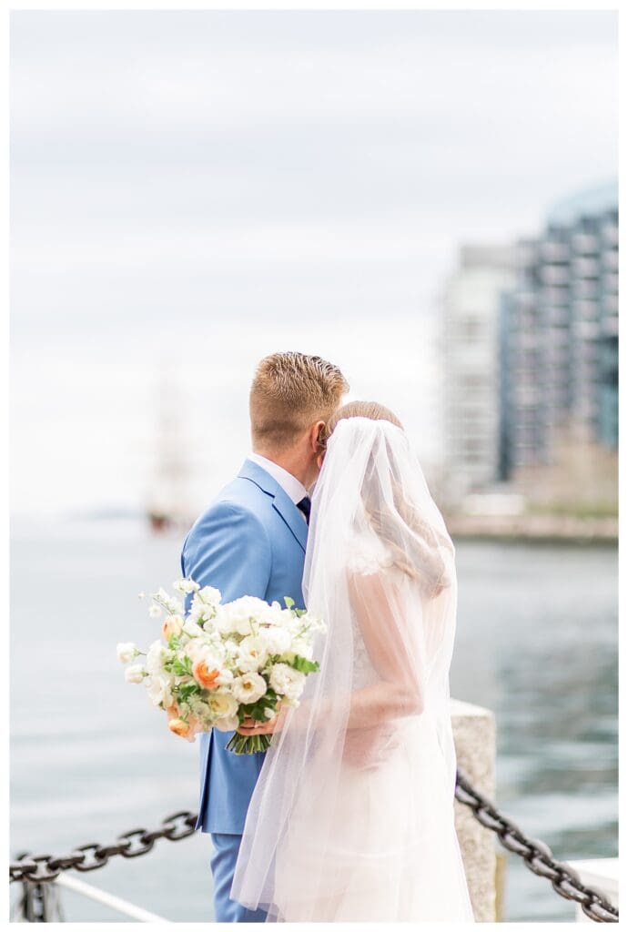 Bride and groom standing together on Boston Harbor Hotel waterfront dock