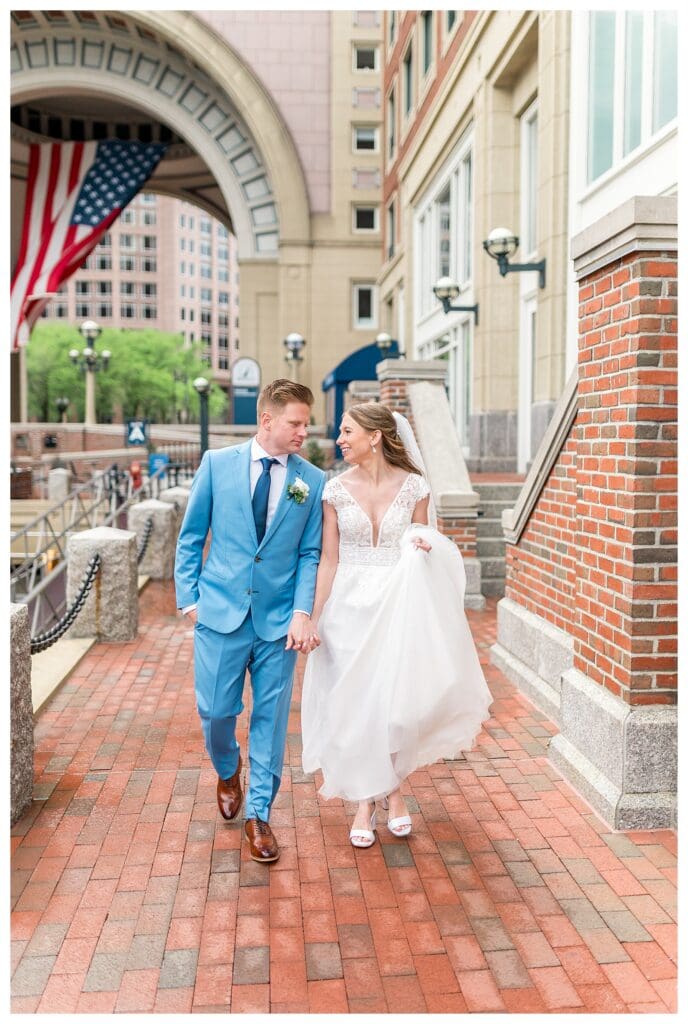 Bride and groom walking together along Boston Harbor Hotel waterfront