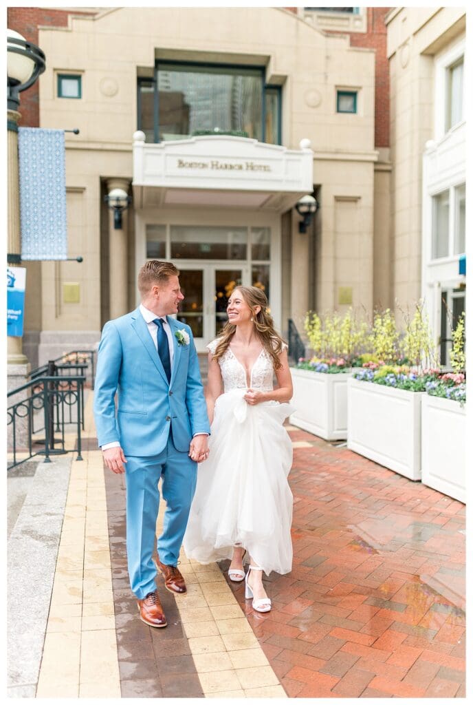 Bride and groom walking together outside Boston Harbor Hotel entrance