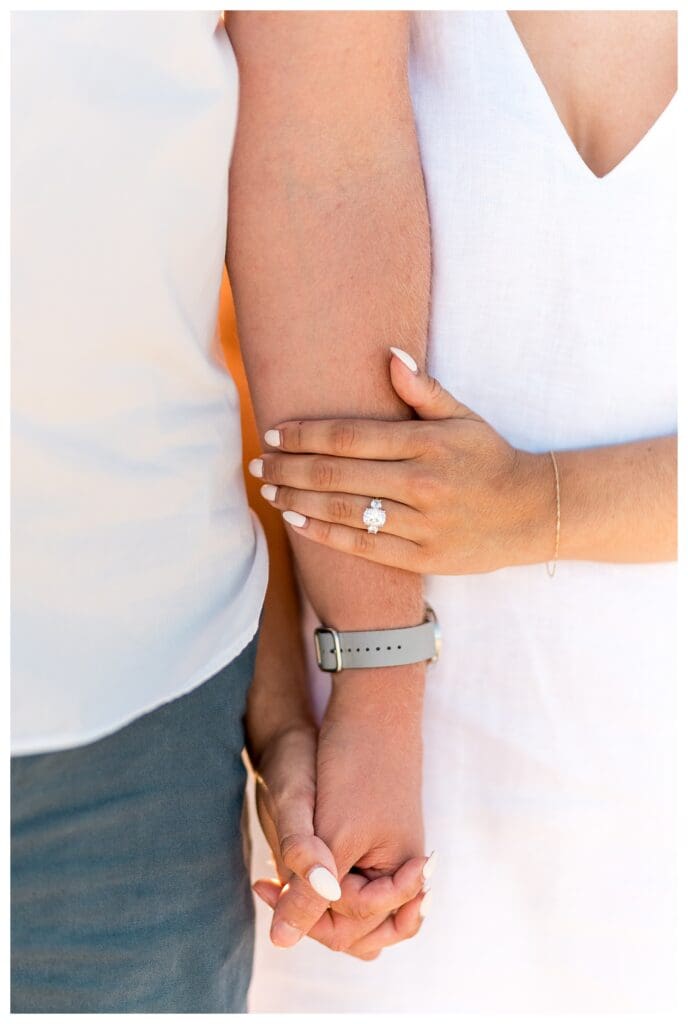 Close-up of an engagement ring and intertwined hands during beach photos