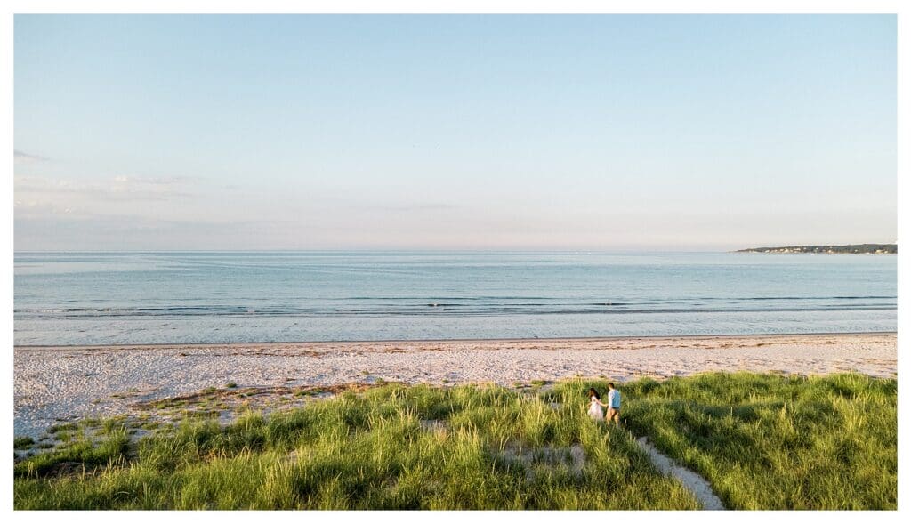 Walking together through the beach grass during an engagement session
