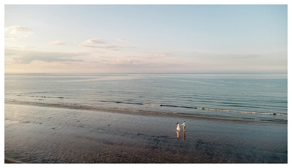 Running toward each other at the edge of the water during Massachusetts beach engagement photos
