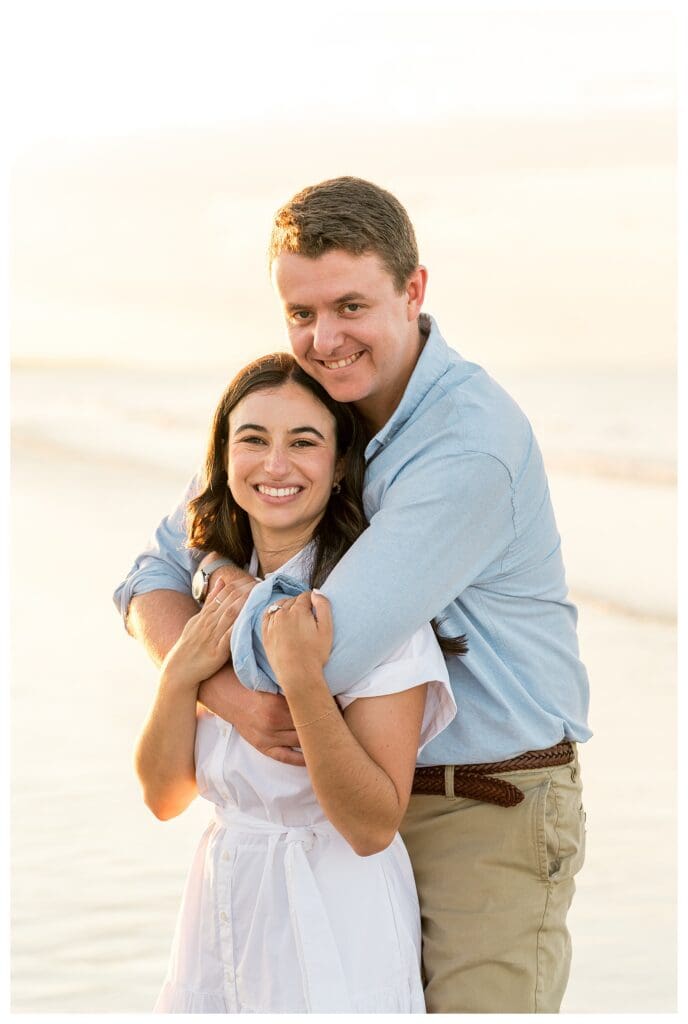 Embracing while standing in the shallow water during a Massachusetts beach engagement session