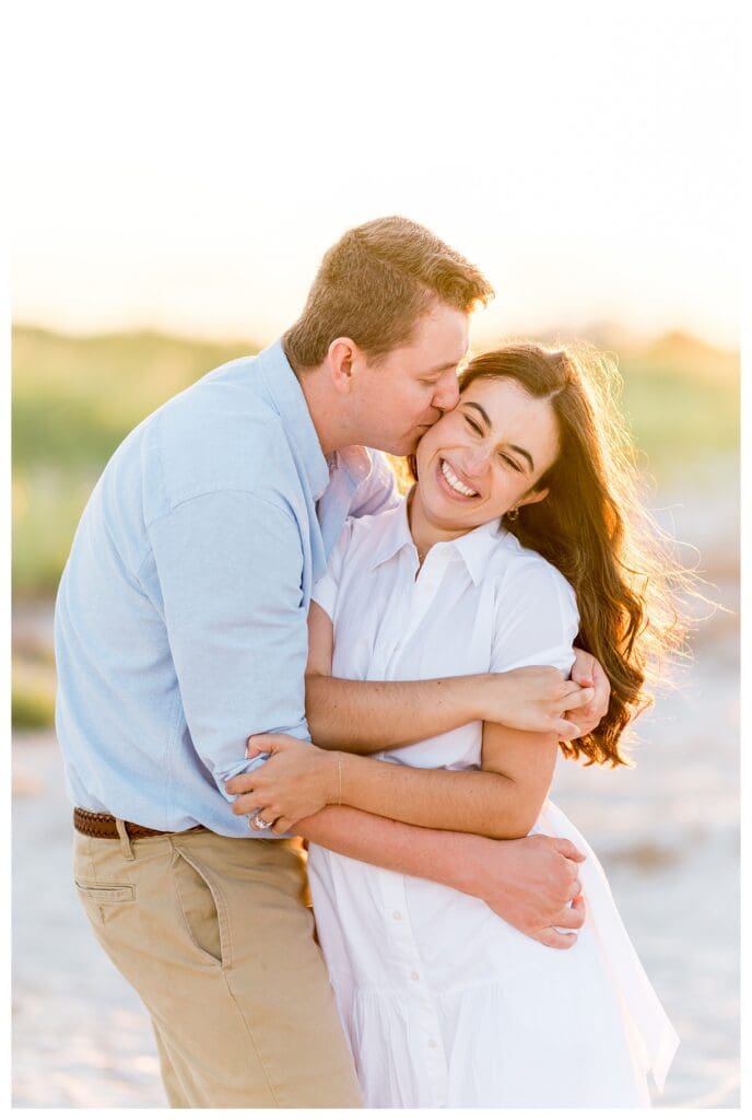 Laughing together while embracing on the beach at sunset