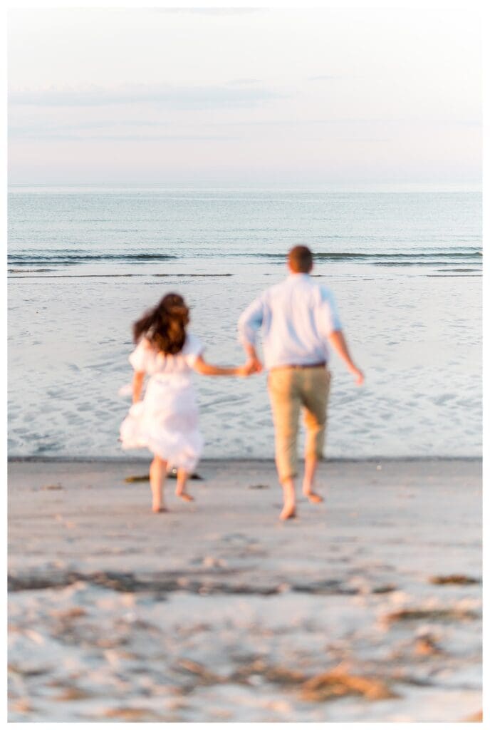 Running toward the ocean hand in hand during sunset
