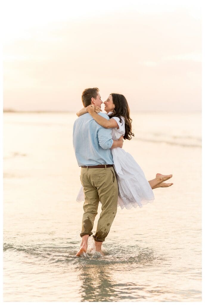 Partner lifting the other while kissing on the beach