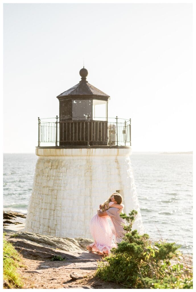 Woman hugs her fiancé at the base of Castle Hill Inn Lighthouse right after the proposal.